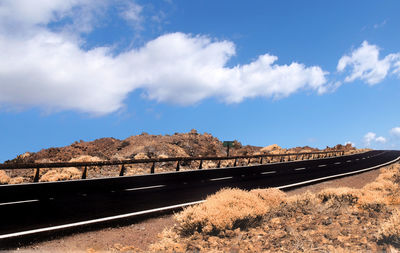 Road leading towards mountain against sky