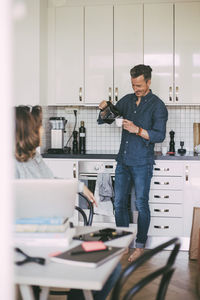 Man pouring coffee having fun conversation with woman at home