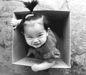 High angle portrait of cute baby girl sitting in cardboard box