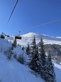 Ski lift over snow covered mountains against sky