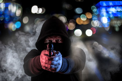 Portrait of criminal wearing mask while aiming gun