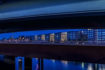 Illuminated city by river against sky at night