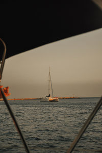 Sailboat sailing on sea against sky during sunset