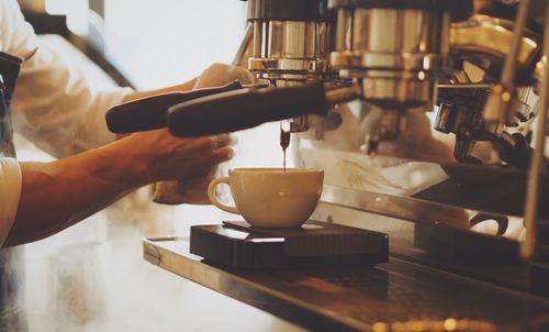 Close-up of man pouring coffee in cafe