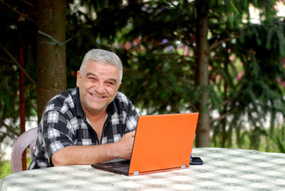 Portrait of man using mobile phone while sitting on table