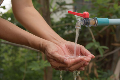 Cropped image of woman washing hands below faucet