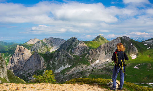 Rear view of man standing on mountain against sky