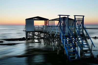 Pier over sea against clear sky during sunset