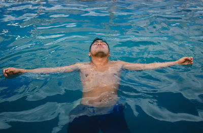 High angle of shirtless man swimming in pool