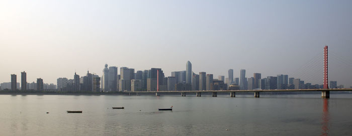 Sea and buildings in city against clear sky