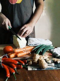 Midsection of woman cutting cabbage at table