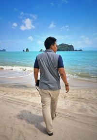 Rear view full length of young man walking at beach