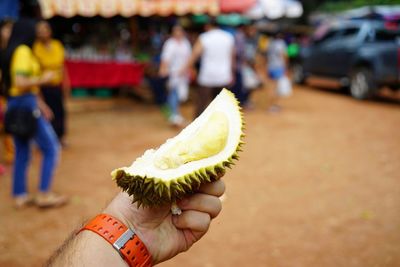 Men holding hands at the ready to eat fruit on hand in the market.