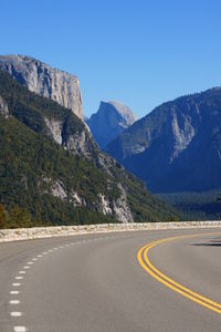 Road amidst mountains against clear blue sky
