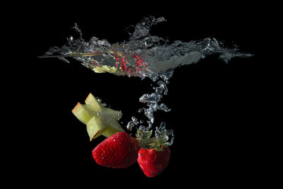 Close-up of strawberry over water against black background