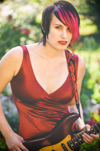 Close-up portrait of woman with dyed hair holding guitar