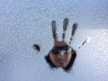 Person seen through snow handprint on glass