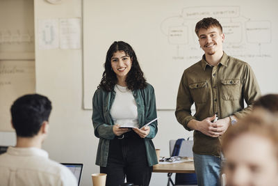 Portrait of smiling male and female university students standing in classroom