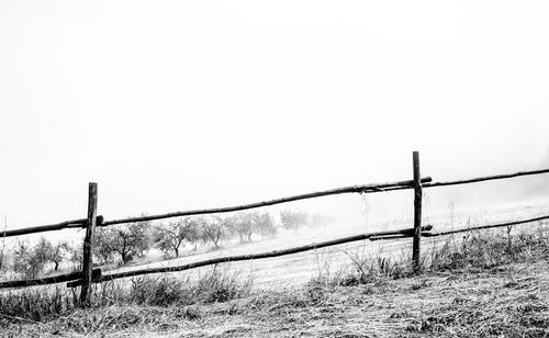 Fence on field against clear sky