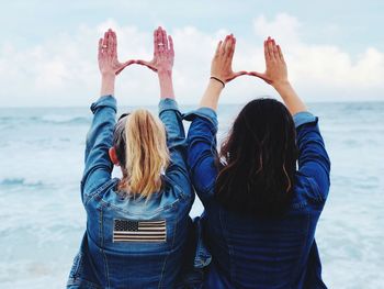 Rear view of female friends gesturing at beach