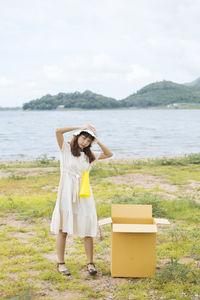 Full length of woman standing at sea shore against sky