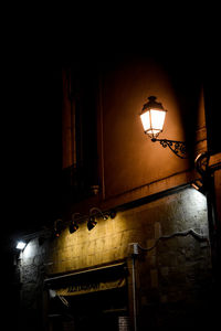 Low angle view of illuminated street light against wall