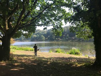 Rear view of man standing by lake