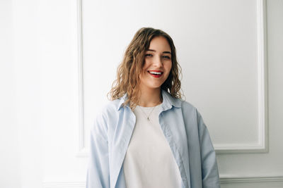 Portrait of young woman standing against wall