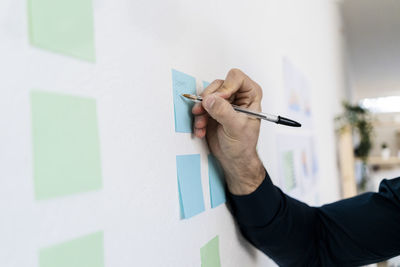 Male entrepreneur planning strategies on notes at wall in office