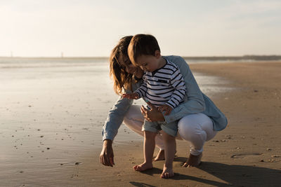 Mother and son playing with sand at beach