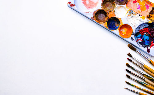 High angle view of paintbrush and artist's palette on white background