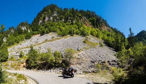 Rear view of man walking on mountain against clear blue sky