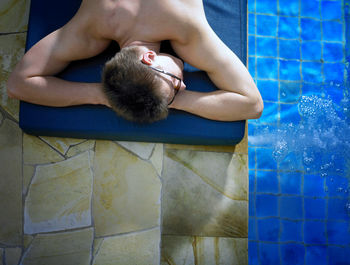 Shirtless man lying on poolside