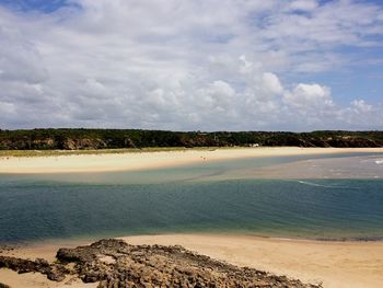 Scenic view of beach against cloudy sky