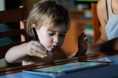 Cute boy using digital tablet on table at home