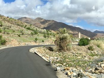 Road leading towards mountains against sky