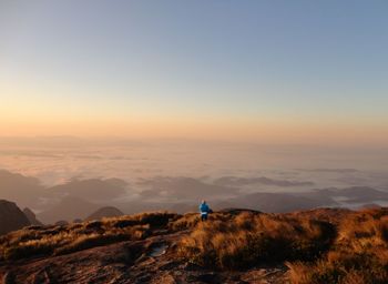 Rear view of man standing on mountain against sky