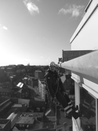 Man photographing against sky in city