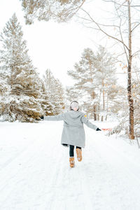 Rear view of woman walking on snow covered trees