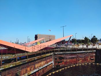 Bridge over river by buildings against clear blue sky