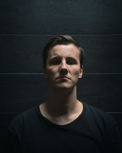 Portrait of young man against black background