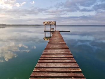 Wooden jetty on pier in lake against sky