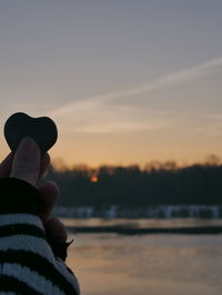 Silhouette woman hand against sky during sunset