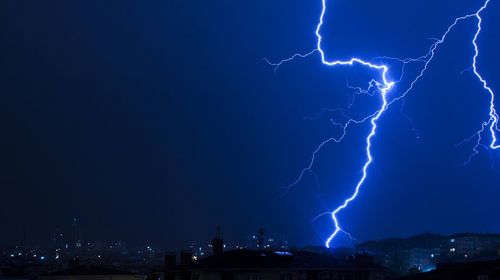 Low angle view of lightning over buildings in city at night