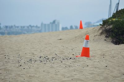 Traffic cones on sand at beach against sky