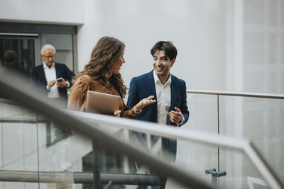 Mature businesswoman talking with happy male colleague at lobby