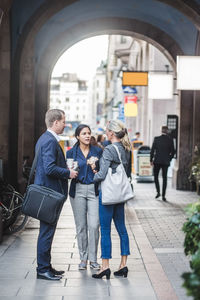 Mature businesswoman standing with coworkers in city