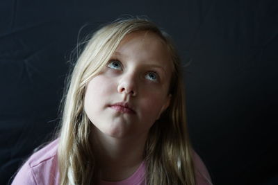 Close-up portrait of a teenage girl against black background