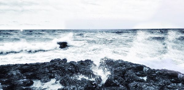 Waves splashing on sea against sky