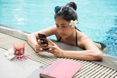 Woman using smart phone by pool